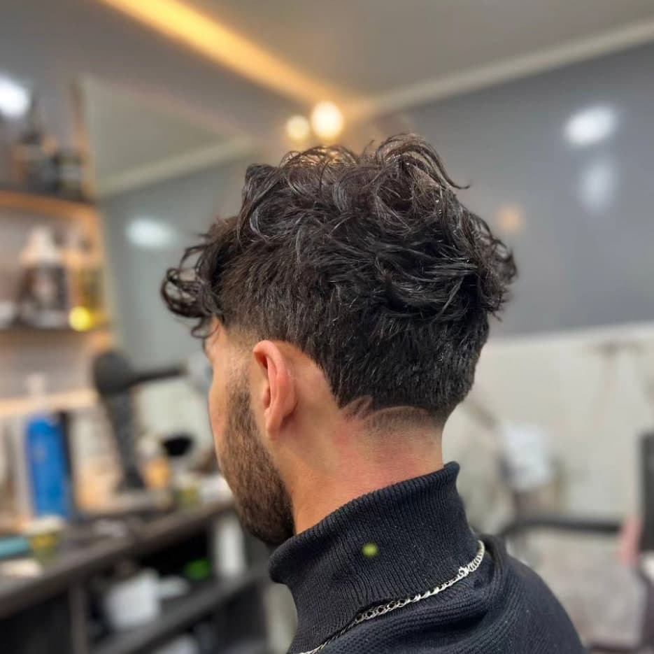 Ցածր taper fade սանրվածք՝ ծավալուն գանգուրներով վերևում, կողքի տեսք